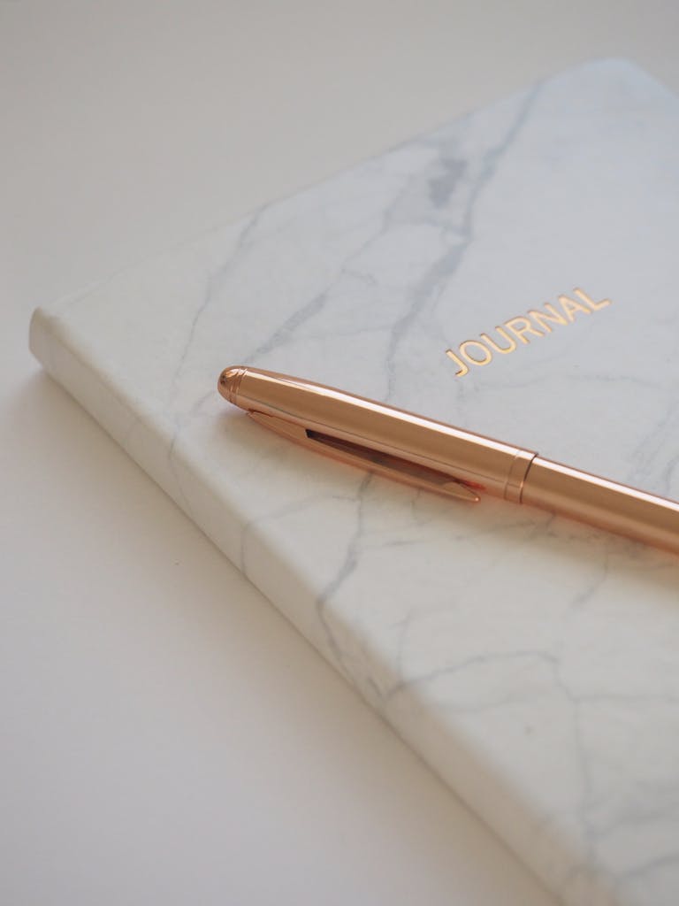 Minimalist marble journal with a gold pen, perfect for elegant stationery and writing inspiration.
